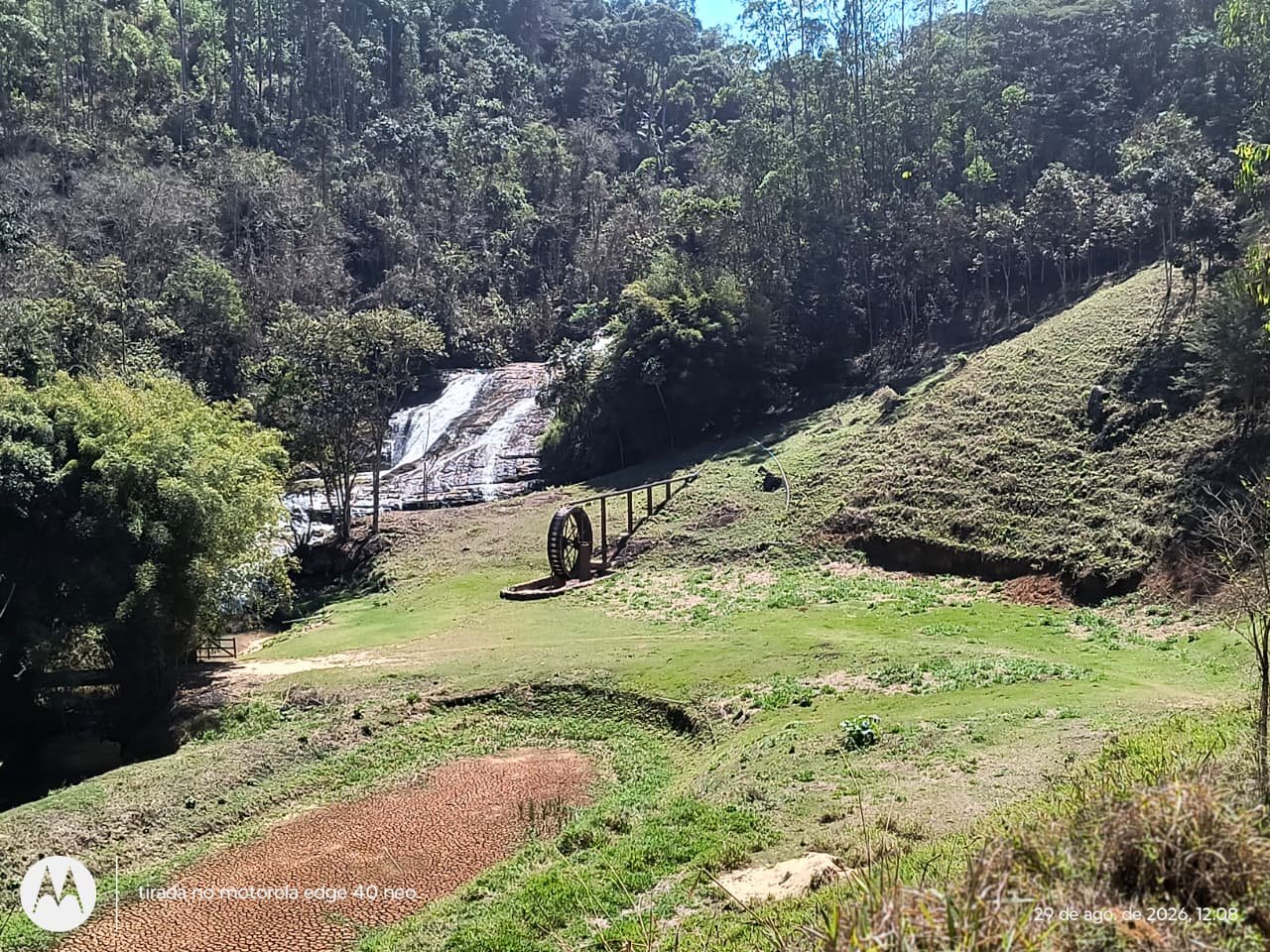 Cachoeira com gramado e roda d'água de madeira na beira
