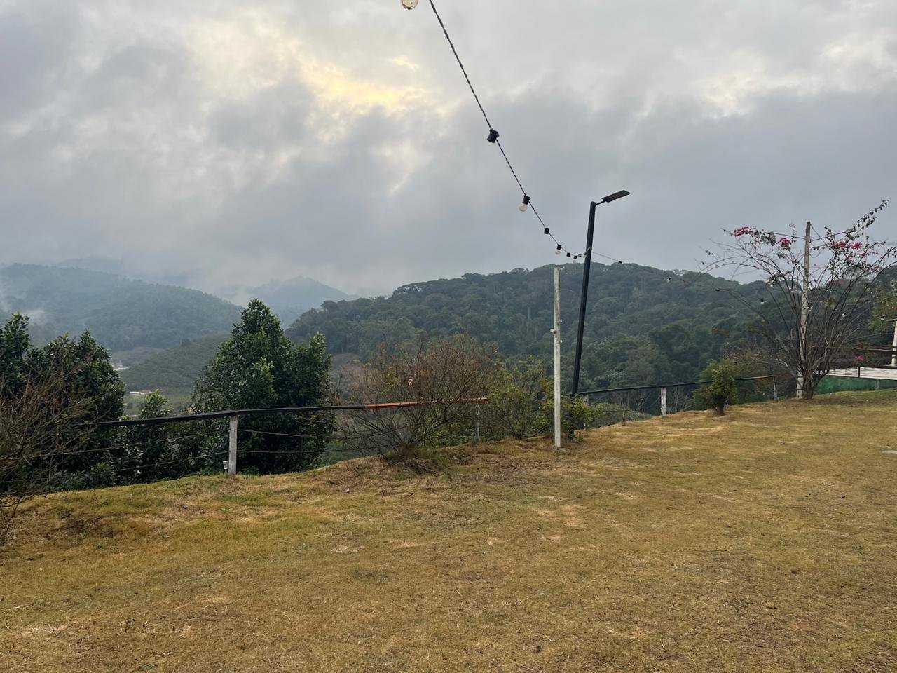 Gramado aberto com varal de luzes e o vale ao fundo