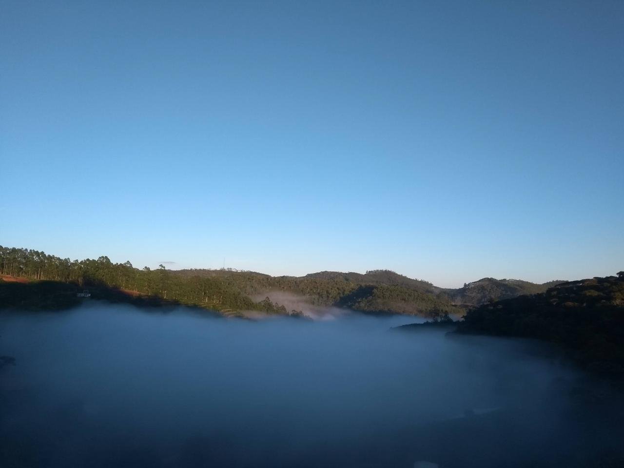 Neblina baixa no vale em manhã de céu limpo