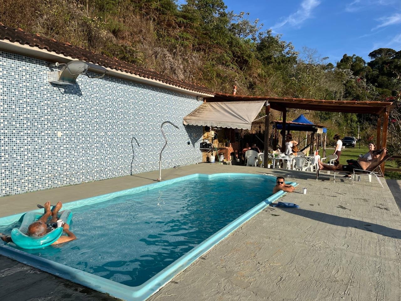 Piscina cheia em dia de sol, com hóspedes