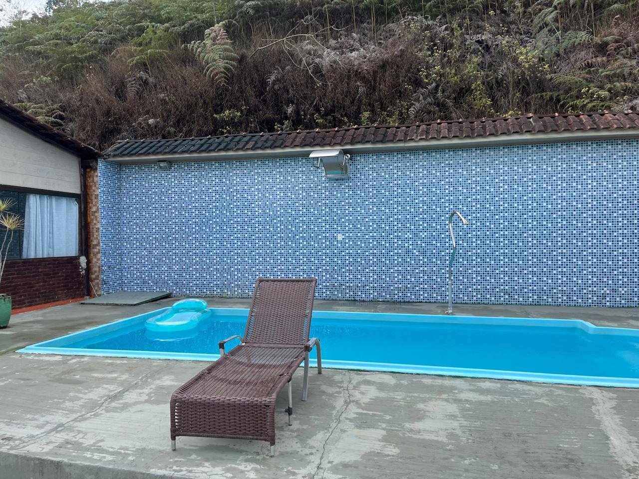 Piscina azul com espreguiçadeira e parede de azulejo